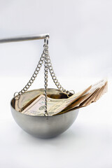 Financial balance concept with dollar bills on hanging scale closeup.