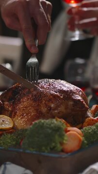 Vertical slow motion video carving roasted turkey on festive table with vegetables holiday dinner celebration thanksgiving or christmas family feast cozy atmosphere warm light joyful evening