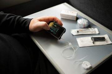 Checking insulin pump screen and preparing diabetes supplies while traveling by train

