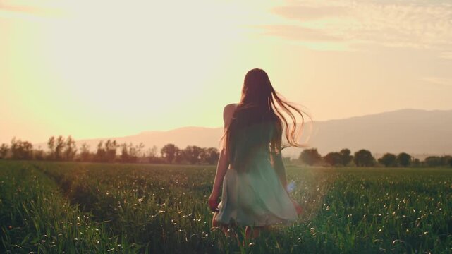 young woman walking through green field in golden sunset light cinematic luxury lifestyle concept freedom elegance mindfulness feminine energy emotional balance slow motion video