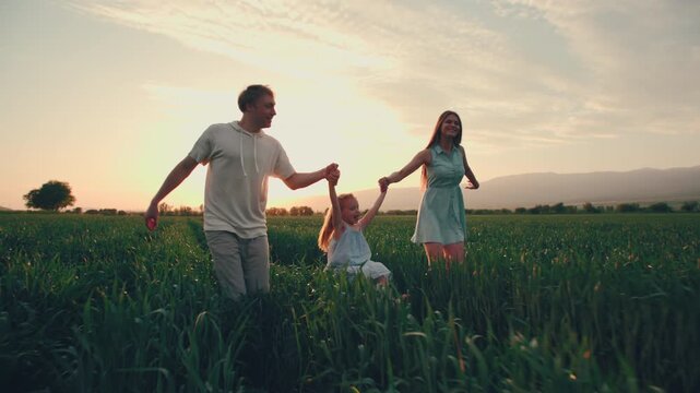 happy family running across green field holding hands smiling and laughing cinematic slow motion concept of love connection freedom and joyful childhood in golden sunset lifestyle video