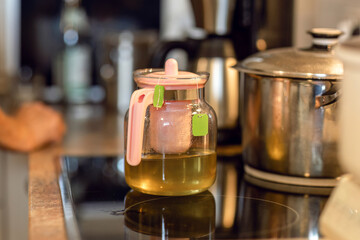 Vintage glass teapot brewing fresh herbal tea on a warm kitchen stove