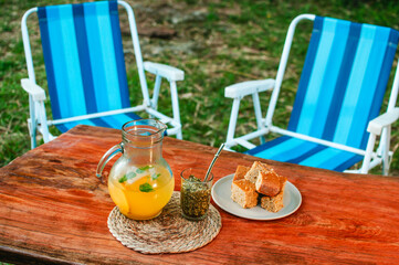 Un tereré de naranjas con bocadillos sobre la mesa rústica en el jardín de la casa, merienda al aire libre