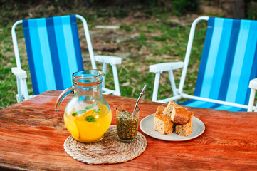 Un tereré de naranjas con bocadillos sobre la mesa rústica en el jardín de la casa, merienda al aire libre