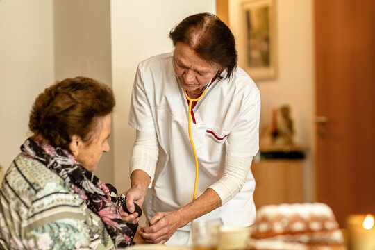A home care nurse measures an elderly woman’s blood pressure as part of cardiovascular health monitoring.