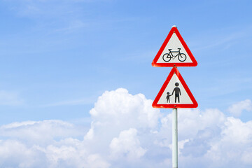 School roadside warning sign students or people crossing with blue sky cloud white is background. Symbol icon bicycle white triangular aluminum, red post about pedestrian crossing road sign traffic.
