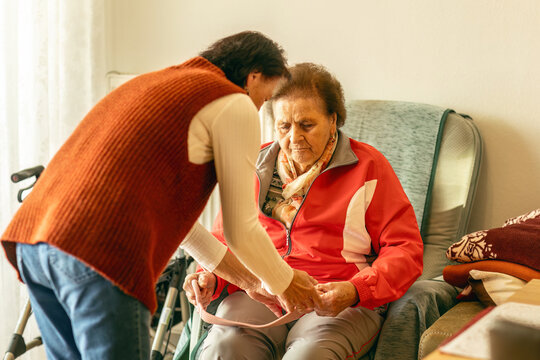 Woman assisting senior with light fitness device to support mobility and prevent contractures - Powered by Adobe
