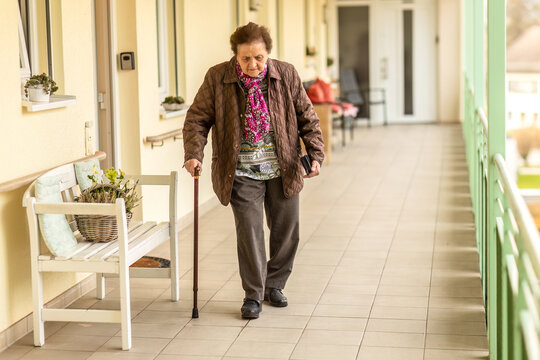 A senior woman walks carefully with a cane, showing mobility support and gait insecurity. - Powered by Adobe