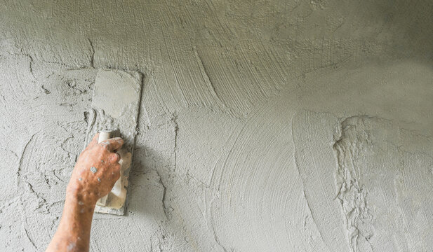 Plaster cement wall background, Hand worker holding handle trowel plastering polish grey mix mortar concrete fresh texture, Equipment people job construction house site masonry structure