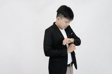 A focused young Asian professional adjusting a wristwatch on their sleeve, conveying a sense preparation, or time management against a clean white studio background