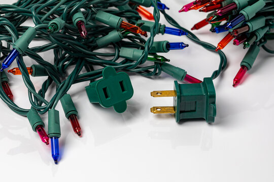 Mini Christmas string lights outlet plug isolated on white background. Holiday decoration safety, inspection and lighting concept.