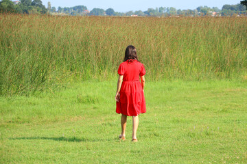 woman in red dress walking through greenery