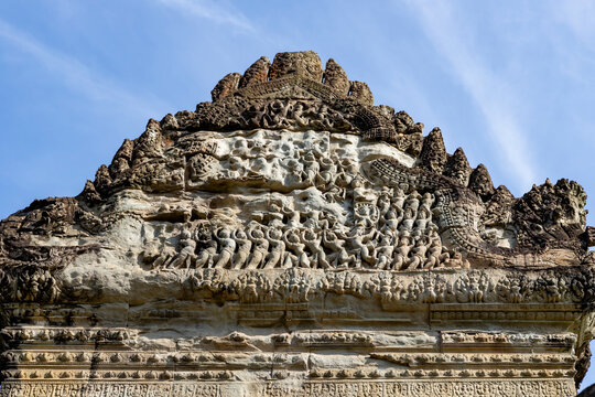 Angkor wat ornate pediment shows the churning of the ocean of milk relief with naga and figures under a blue sky in siem reap, cambodia