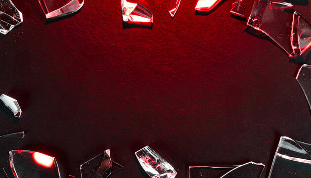 Shattered glass pieces illuminated with red light on dark textured background
