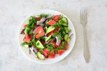 Fresh Tomato and Cucumber Salad with Red Onion and Herbs with a fork top view