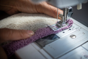 An Asian mother sewing clothes with a sewing machine at home, showing love and care for her family while saving money during tough economic times. The concept of thrift, sustainable living, and simple