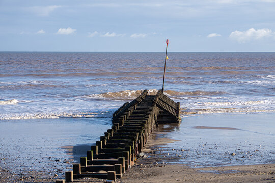 Hornsea Groyne and Marker &mdash; Coastal Scene with Wooden Structure, Calm Sea, and Navigational Signage