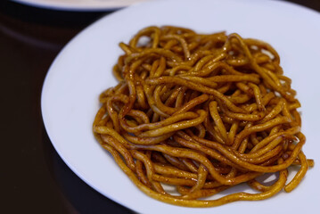 A close-up of thick, chewy Shanghai Fried Noodles coated in a rich, dark soy sauce. This simple, appetizing image represents a classic style of Chinese comfort food