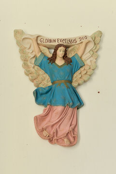 religious decoration, Religious wall carving of an angel holding a banner inscribed "GLORIA IN EXCELSIS DEO", traditional folk art sculpture, vertical

