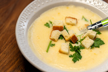 A close-up view of a creamy soup served in a white bowl on a rustic wooden table