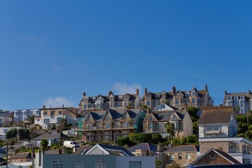 A neighborhood of houses situated on a hill. The houses vary in size, style, and color, with a blue...