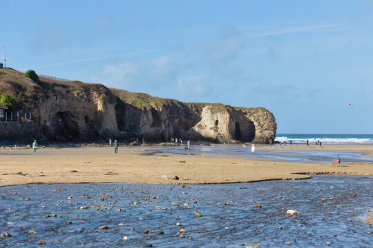 A wide sandy beach leads to rocky cliffs and the ocean in Perranporth - Cornwall - UK