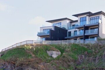 Luxury seaside condos sit atop a green cliff. The modern architecture offers scenic coastal views