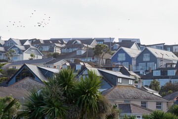 Rows of houses cluster on a hillside, mostly white with blue accents and dark roofs, evoking a peaceful seaside town in Perranporth - Cornwall - UK