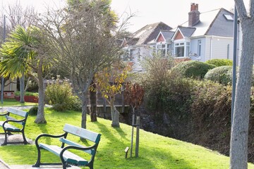 A scenic park featuring a grassy lawn, benches, and trees. Houses are visible in the background, indicating a residential area in Perranporth - Cornwall - UK