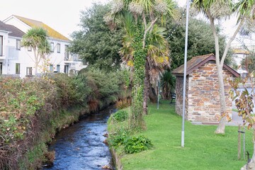 A nature scene uploaded to Adobe Stock. A stream flows next to a building and plants in Perranporth - Cornwall - UK