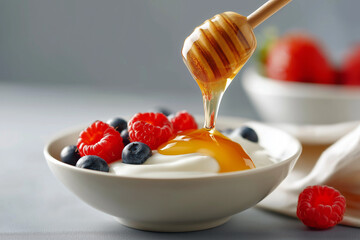 Pouring honey on Greek yogurt bowl with berries