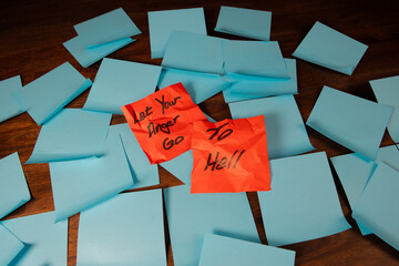 Crumpled red sticky notes on a pile of blue sticky notes a dark wood surface reading 