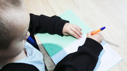 A child sits at a table, focused on writing in a notebook. The scene captures a peaceful moment of learning and creativity in a cozy indoor setting.