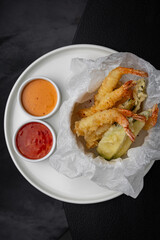 Shrimps in tempura with sauces side by side on a white plate for a menu