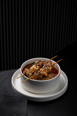 Asian soup with fish and meat skewers on top isolated