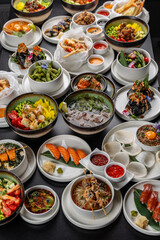 A large table with Asian cuisine. Soups, sushi, appetizers, poke bowls, shrimp, sauces