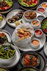 A large table with Asian cuisine. Soups, sushi, appetizers, poke bowls, shrimp, sauces