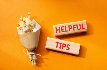 Helpful tips symbol. Wooden blocks with words Helpful tips. Beautiful orange background with bouquet of flowers. Business and Helpful tips concept. Copy space.