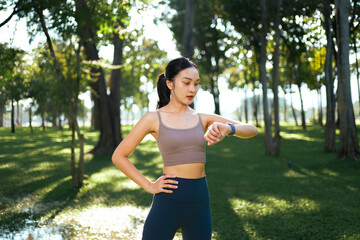 Asian woman checking smartwatch while exercising in park