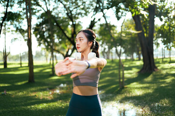 Young asian woman stretching arms outdoors in park