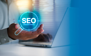 Modern SEO strategy concept with a glowing search icon hovering above a professional's hand beside a laptop, illustrating digital marketing optimization for improving business online visibility