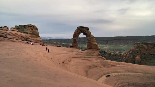 Hiking the trail to Delicate Arch in Arches National Park at dusk, warm evening light casts long shadows over the red rock landscape.