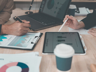 A statistician is preparing charts and documents for a meeting. A team of professionals is reviewing financial documents. Pointing to charts on the desk. Working.