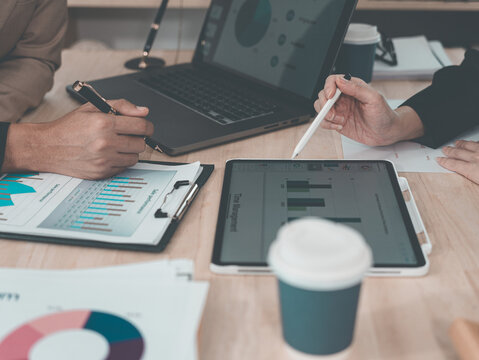 A statistician is preparing charts and documents for a meeting. A team of professionals is reviewing financial documents. Pointing to charts on the desk. Working.