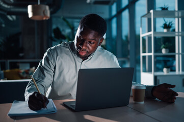 Young african american man working late night in office