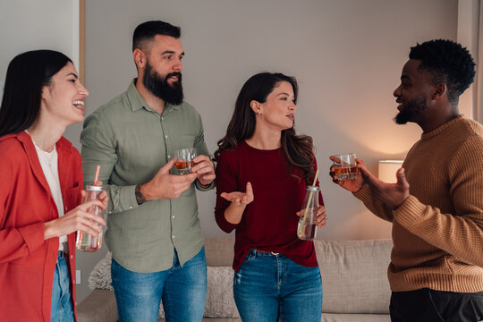Diverse friends talking and drinking at a home party