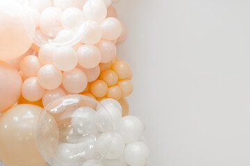 Soft pastel balloon decoration with white, peach and transparent balloons forming an elegant party backdrop on a clean white background.