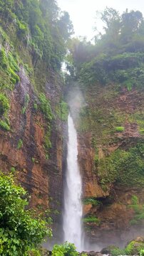 Koban Kapas Biru is a waterfall in the tropical jungles of East Java, descending from a high cliff into a lush green canyon surrounded by tropical forests with vibrant vegetation.Lumajang River. 4К