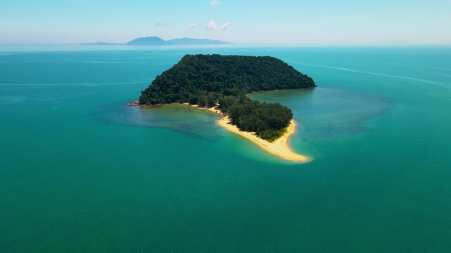 Aerial view of a small tropical island located just off the coast of Pantai Bukit Keluang in Besut, Terengganu. The island is covered in dense green forest and surrounded by vibrant turquoise waters.