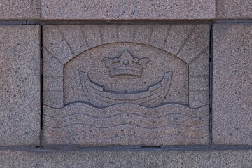Stone carving is a detail from Pitkäsilta (Long Bridge) granite bridge, coat of arms of the city of Helsinki has been carved into stone on the bridge railing, Helsinki, Finland.